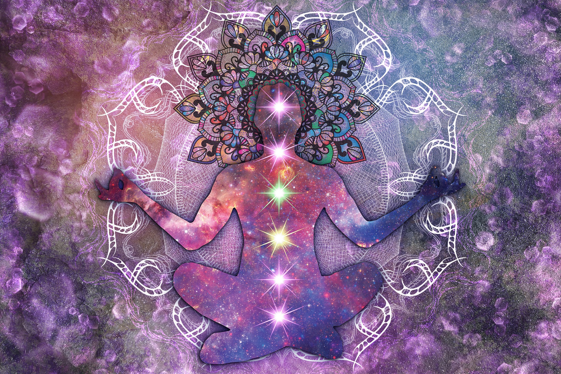 A graphic image of a person of indeterminate sex in a cross-legged yoga position, seemingly in the Cosmos, all the chakras are lit up and the crown area is like an unfolded flower pattern