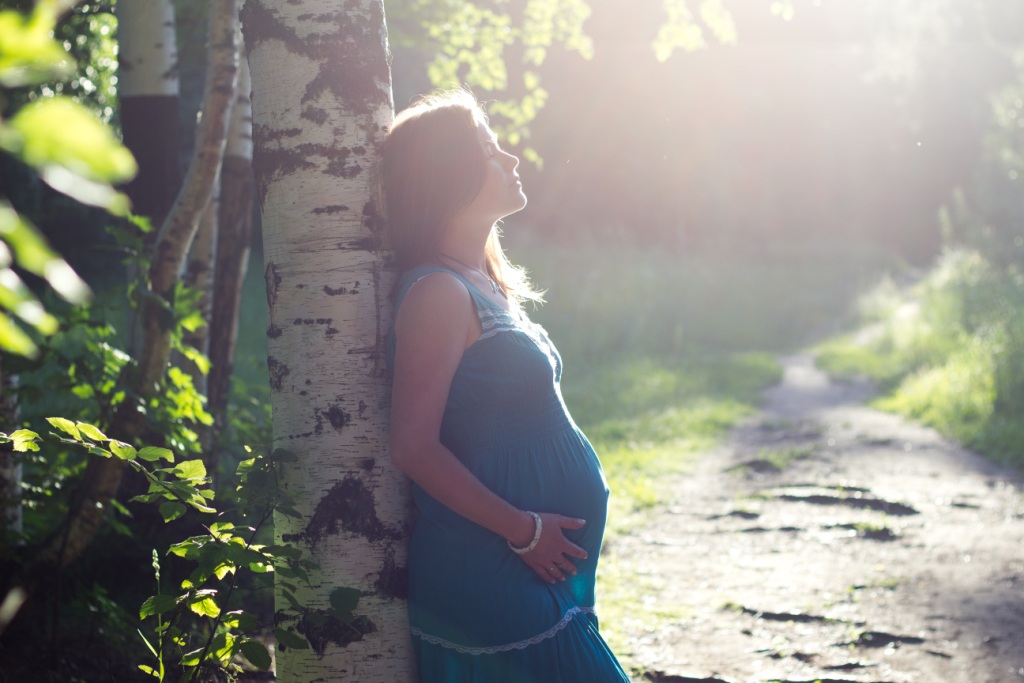 Pregnant mum by tree in sun