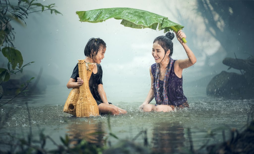 Water everywhere? Joyful woman & child in pond in rain in Cambodia
