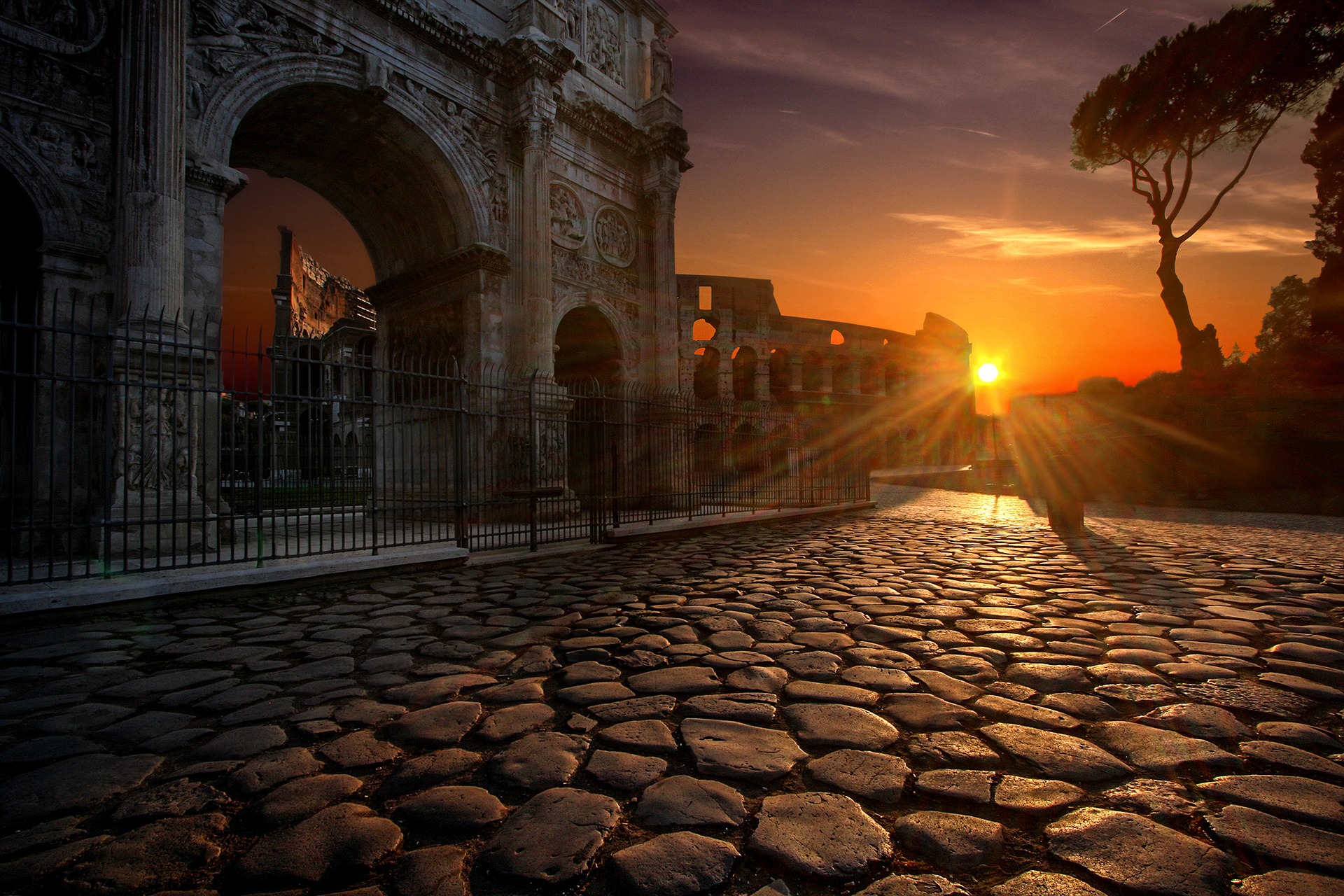 The sun rises over an empty cobbled street in Rome, the Colosseum is in the background