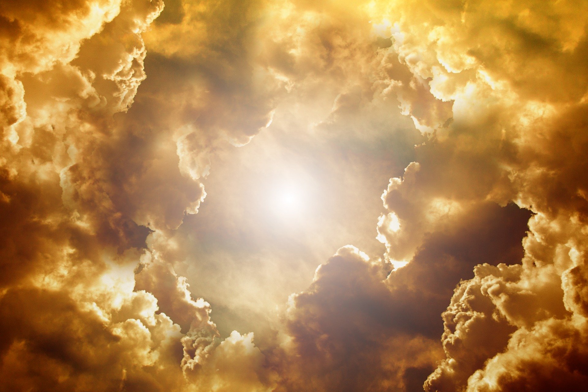 We are looking directly up into a golden sky. The clouds have parted in a circular shape. The sun, as a blinding light, shines forth from high above.