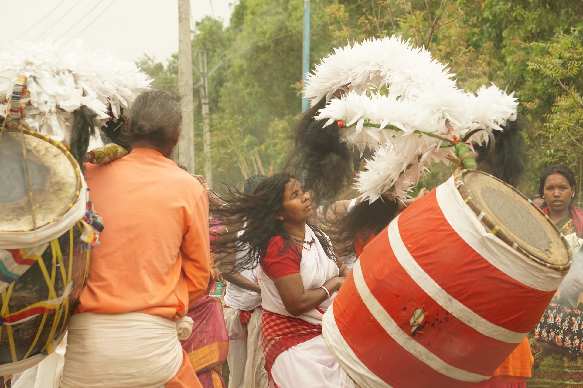 We see a close-up of a festival or ritual in India. Women and men are dancing and large decorated drums are being beaten.