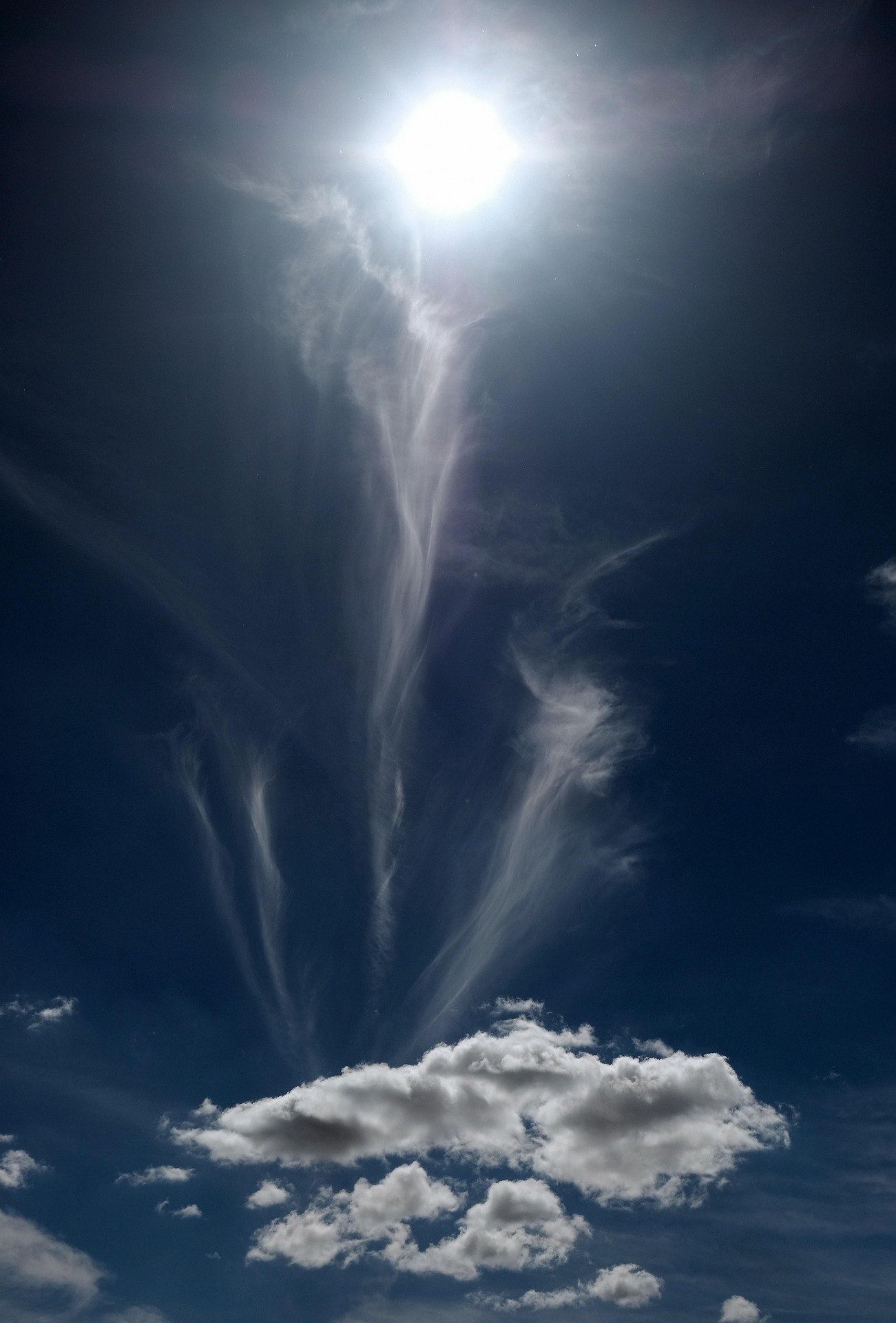 A portrait orientation of the sun - at the very top - banishing various fleeing clouds