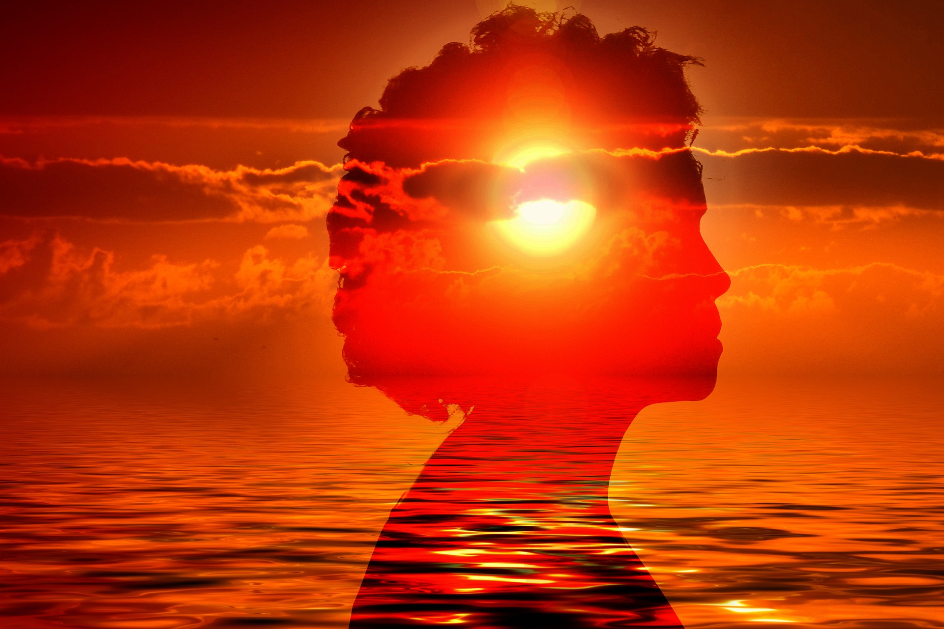 A yellow sun is above the ocean horizon. The sky and water are coloured orange. Superimposed on this image is the reddened yet transparent silhouette of a woman's head in profile. The sun is in the centre of her head. She appears to be meditating.