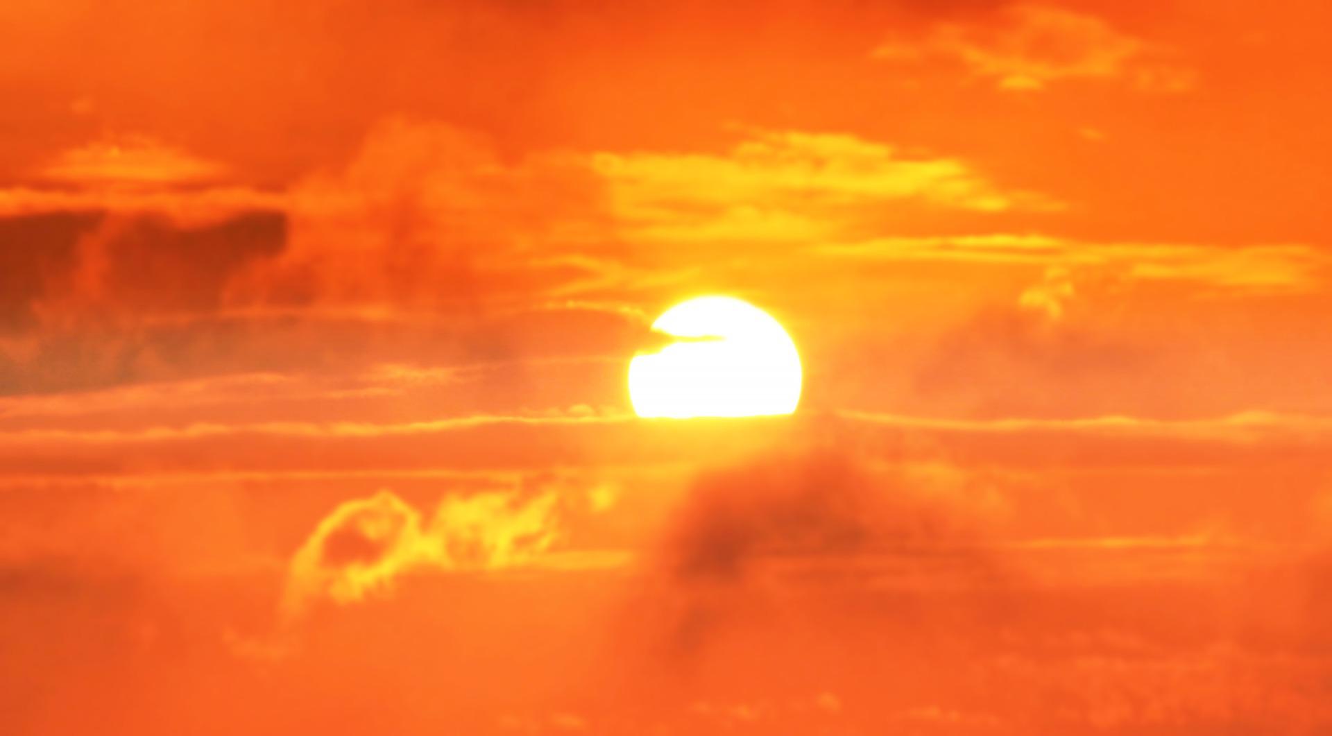 The sun is rising and the sky and a few clouds are very orange-coloured