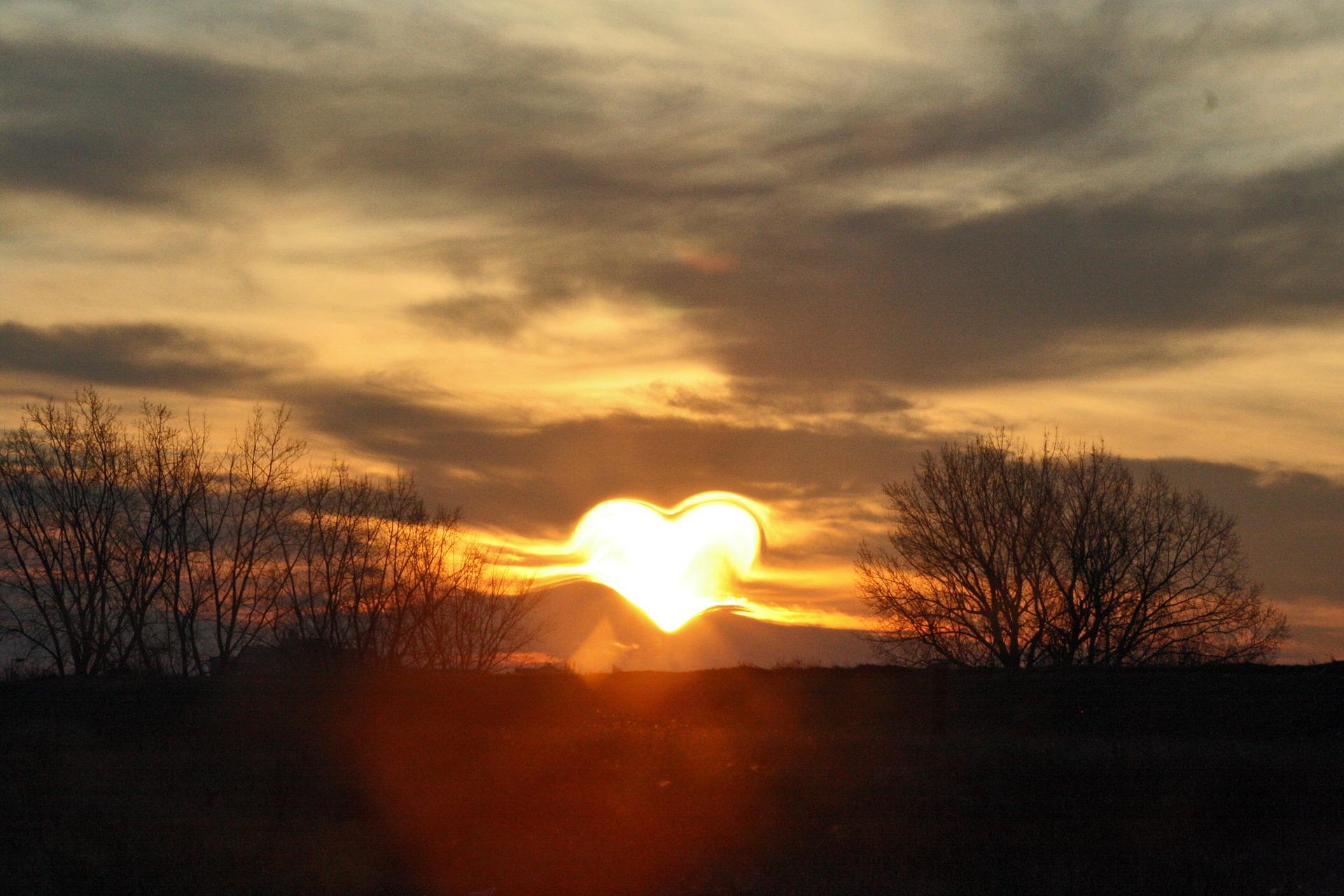 A heart-shaped sun is on the horizon. It is shining its golden light all over the world.