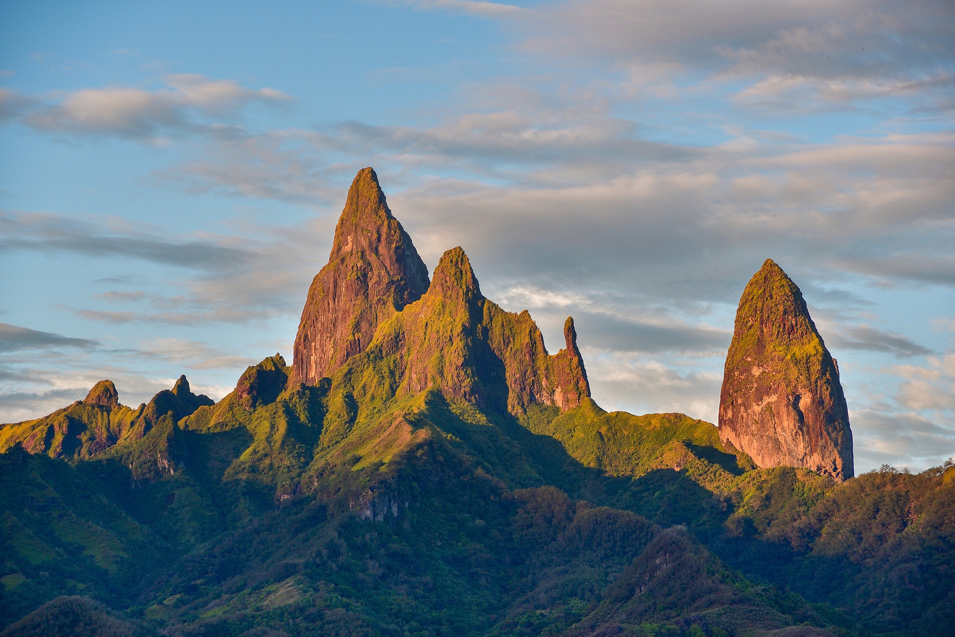 A sunrise visible on tall jagged mountains in French Polynesia - specifically on Ua Pou, the third largest of the Marquesas Islands, French Polynesia