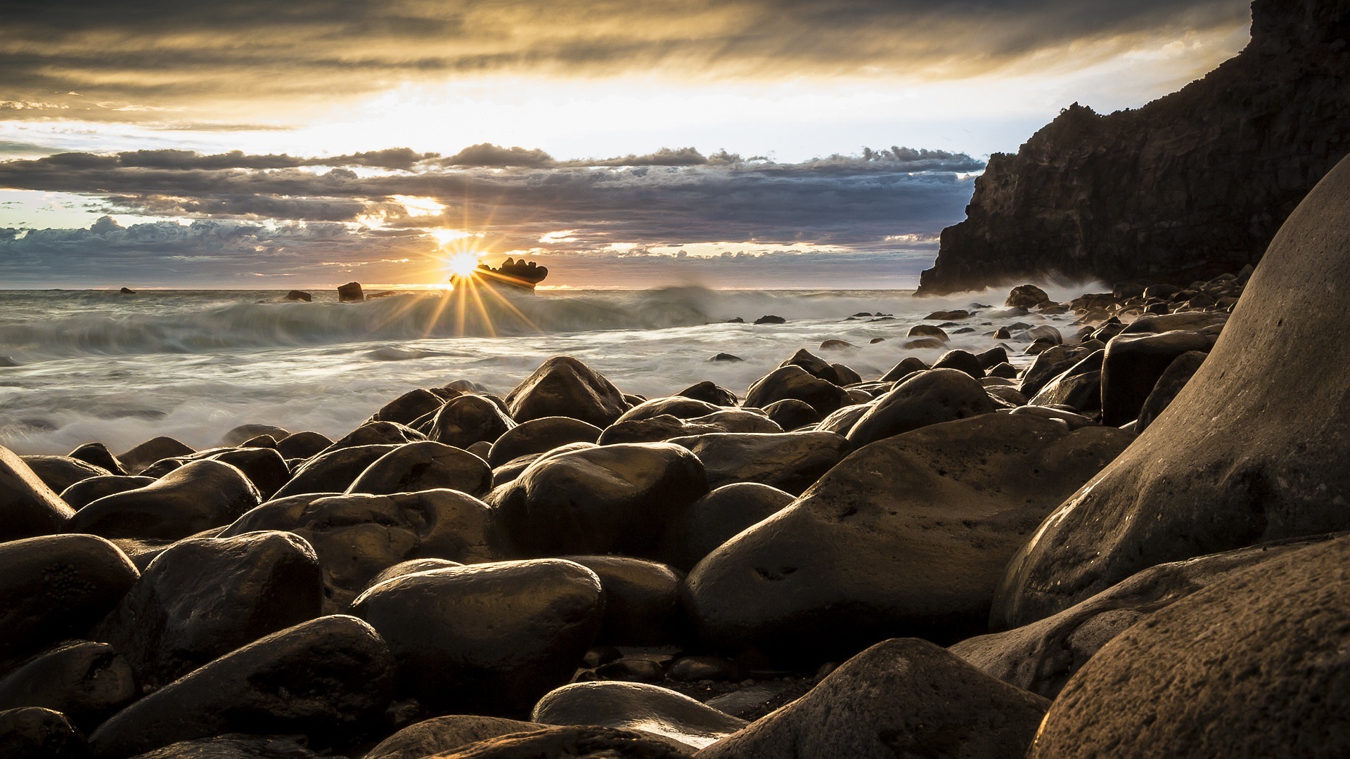 A New Zealnd sunrise over a beach with large smooth rocks