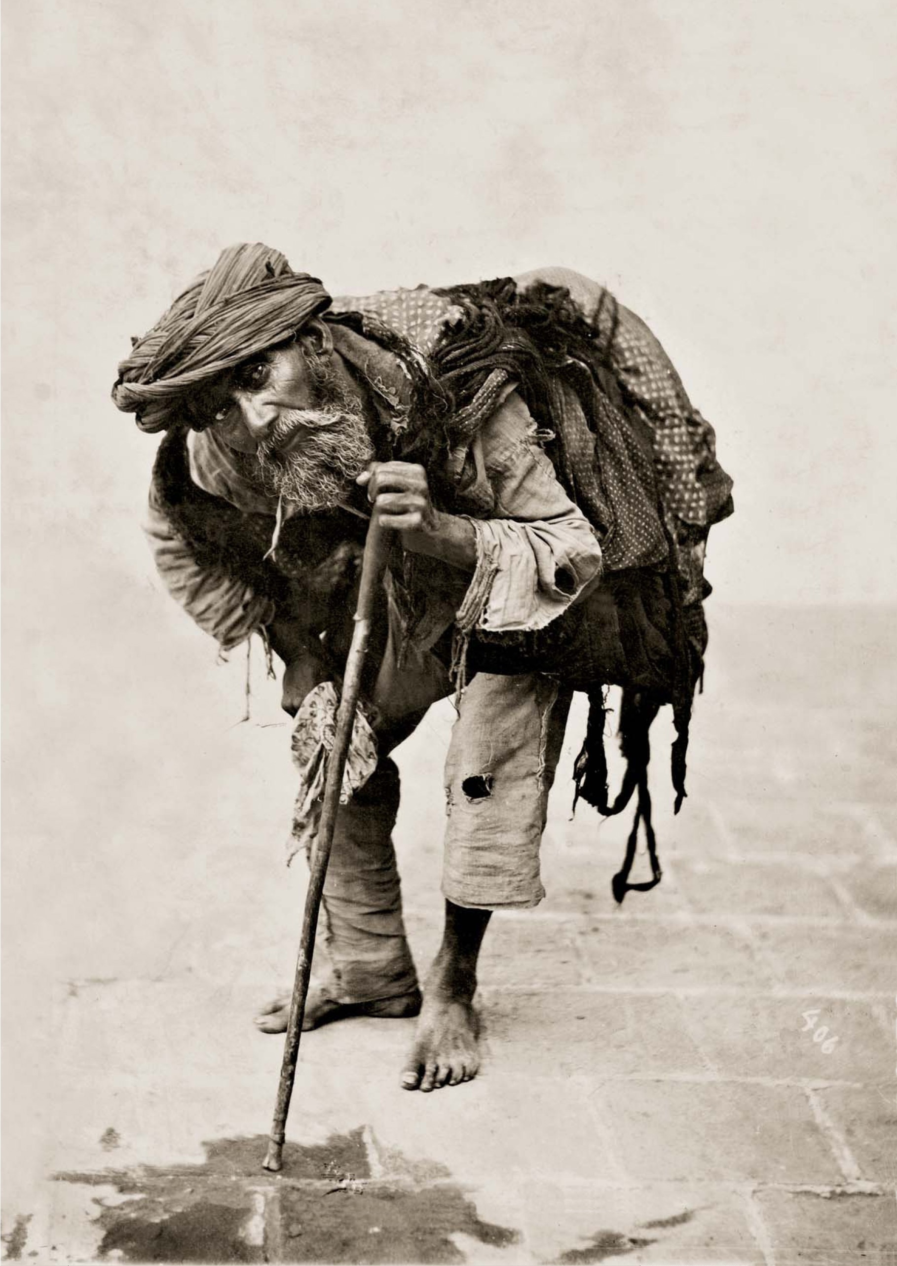 An old man, bent-over with a stick and back pack, in Tehran, Iran