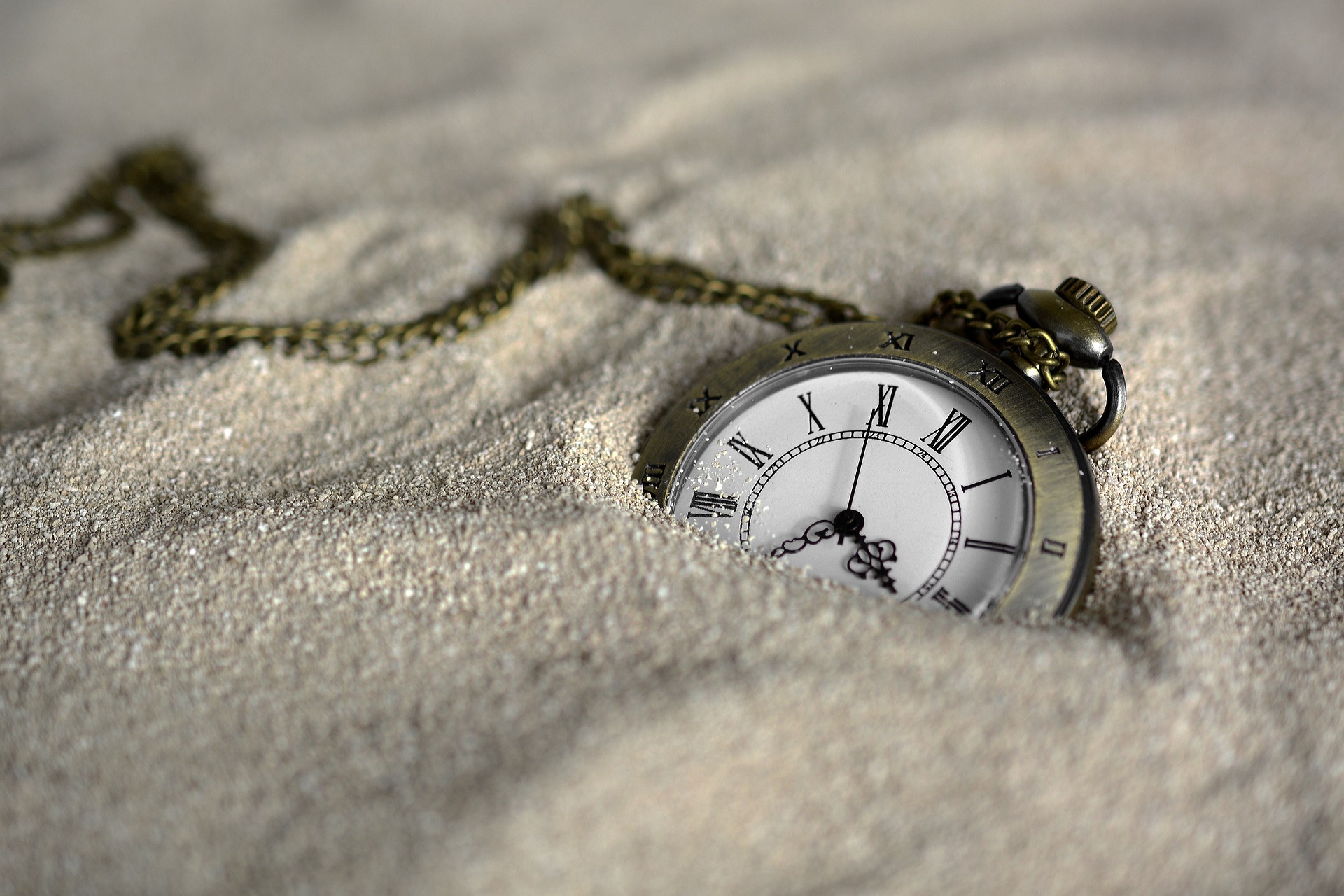 A pocket watch lies half-buried in desert sand. Perhaps abandoned?