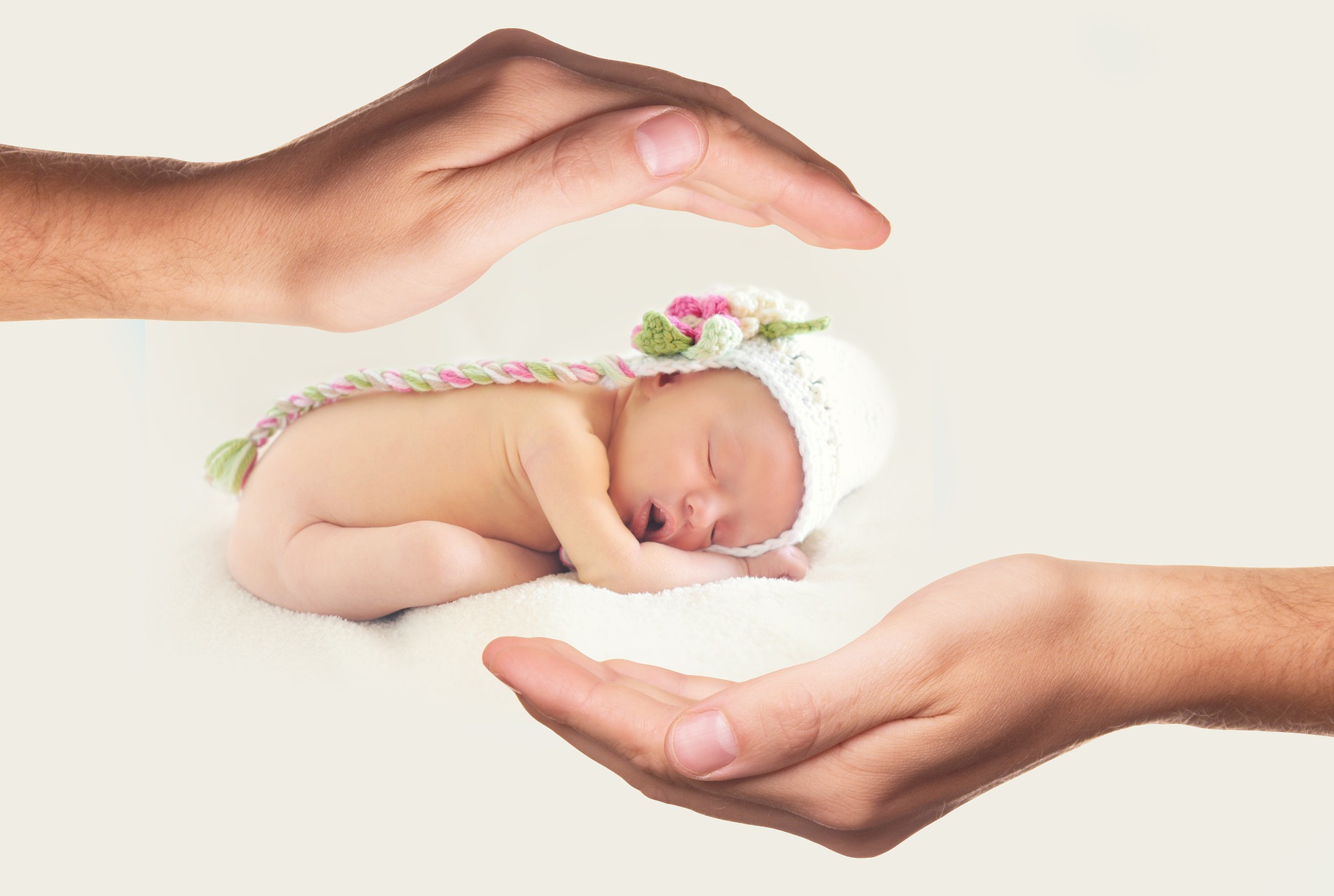 Protective hands around a sleeping newborn baby