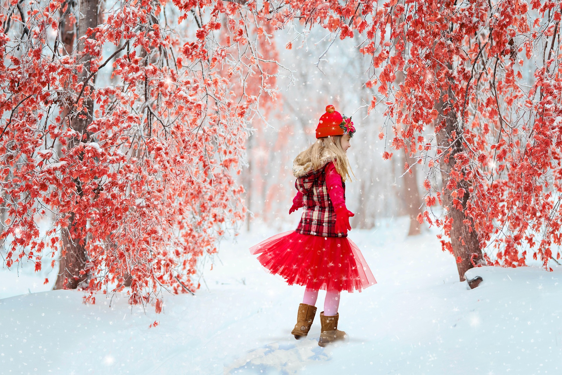 A girl child in red joyously sways through a winter scene with trees with red leaves